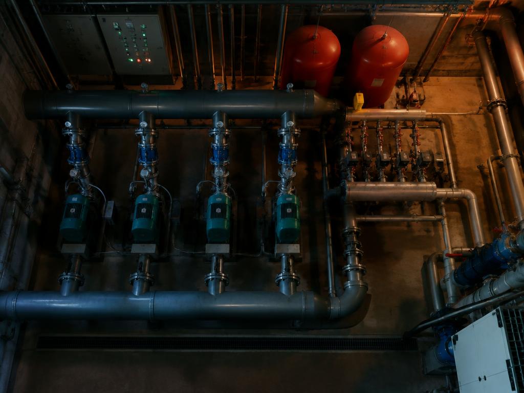 Plant room with a row of circulation pumps, headers and pressurisation vessels